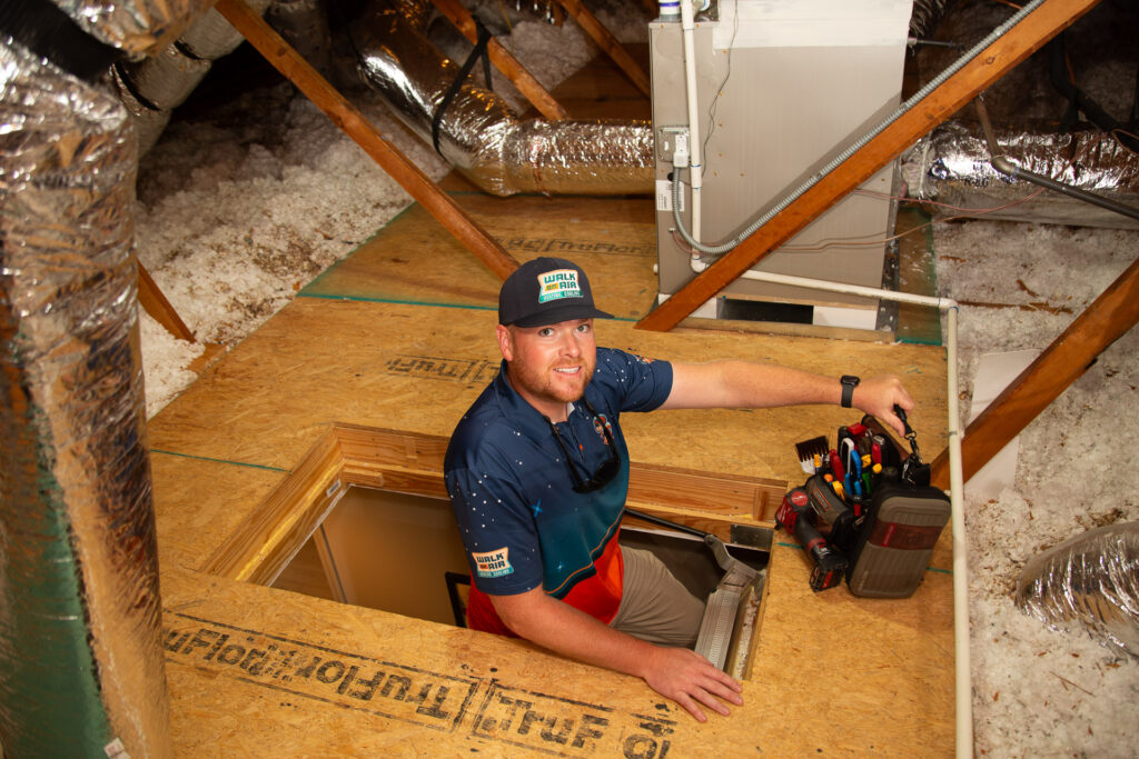 Technician entering a homes attic to check hvac unit